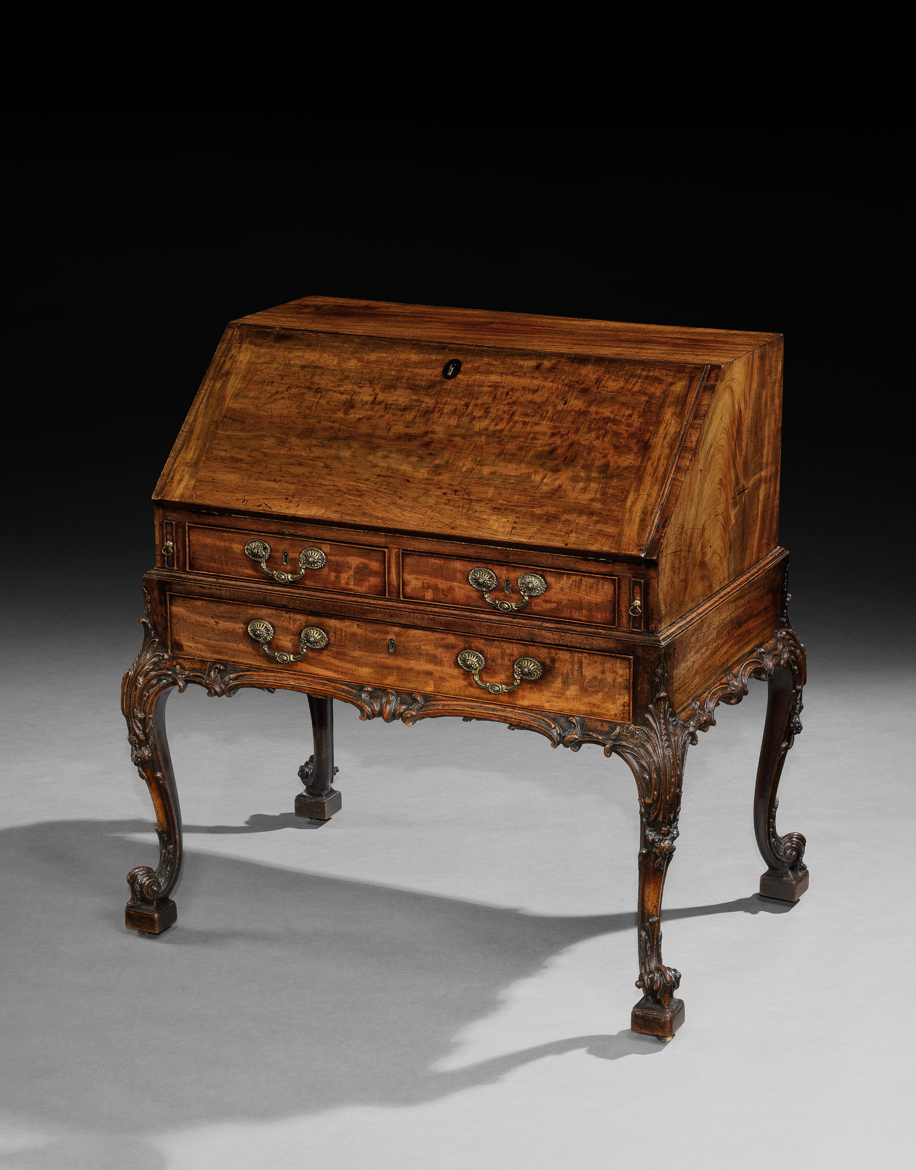 AN EXCEPTIONAL GEORGE III PERIOD CARVED MAHOGANY BUREAU ON STAND